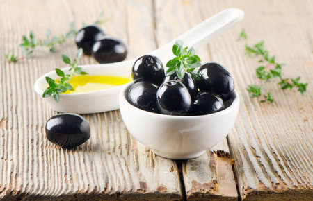 Black olives and thyme on a wooden tableの写真素材