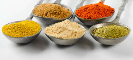 Assortment of powder spices on spoonsの写真素材