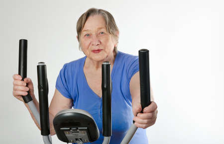 Senior happy  smiling woman on stationary training bicycle
