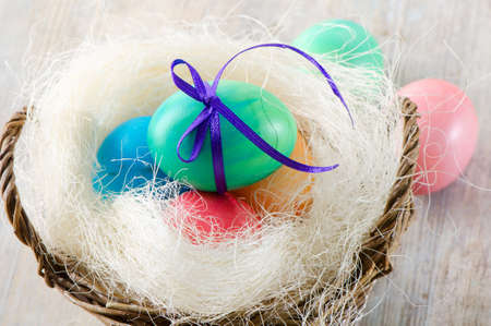 Easter eggs in the basket on a wooden tableの写真素材
