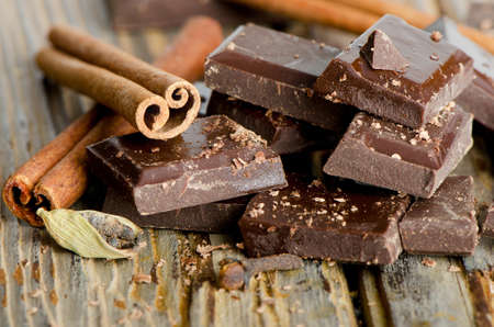 Broken chocolate bar and spices on wooden table. Selective focus