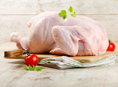 Whole raw chicken  on a wooden tableの写真素材