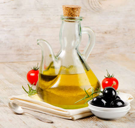 Olive oil and black olives on a wooden tableの写真素材