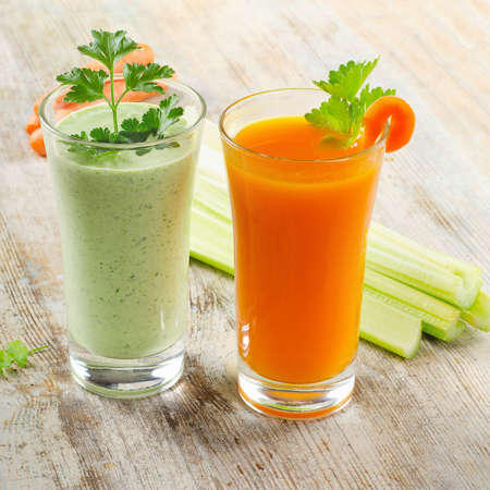 Healthy drinks - Green vegetable smoothie and carrot juice  on a wooden table  selective focusの写真素材