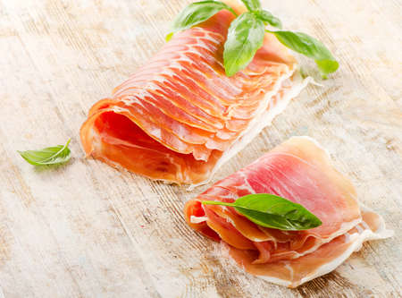 Slices of cured ham on a wooden tableの写真素材