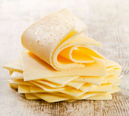 Slices of cheese on a wooden tableの写真素材