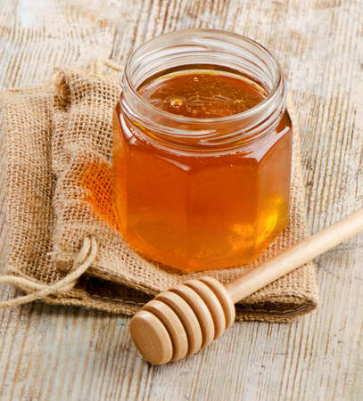 Glass jar of honey with wooden stickの写真素材
