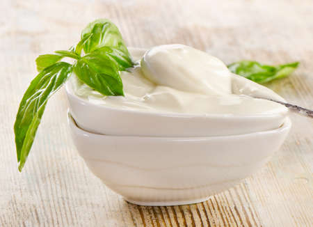 Fresh yogurt with basil on a wooden tableの写真素材