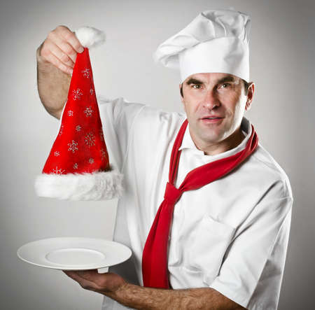 Smiling chef showing empty plate with  Santa hatの写真素材