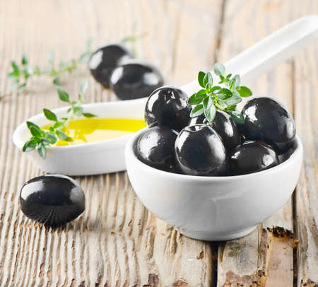 Black olives and olive oil on a wooden tableの写真素材