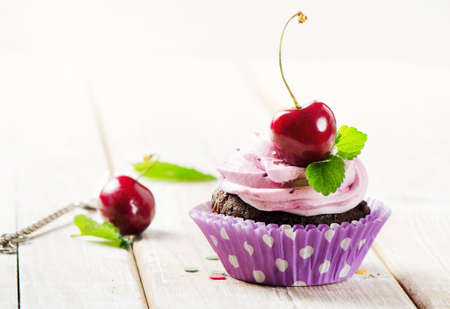 Cupcake with cherry on a wooden tableの写真素材
