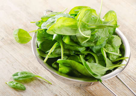 Fresh green spinach leaves on a wooden tableの写真素材