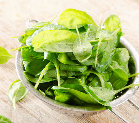 Fresh green spinach leaves on a wooden tableの写真素材
