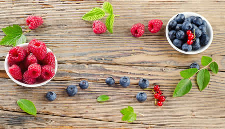 Raspberries and blueberries on wooden tableの写真素材