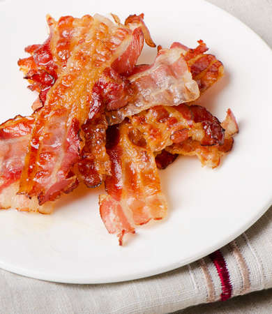 Cooked bacon rashers on a white plate. Selective focusの写真素材