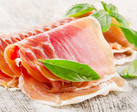Slices of cured ham on a wooden table . Selective focusの写真素材
