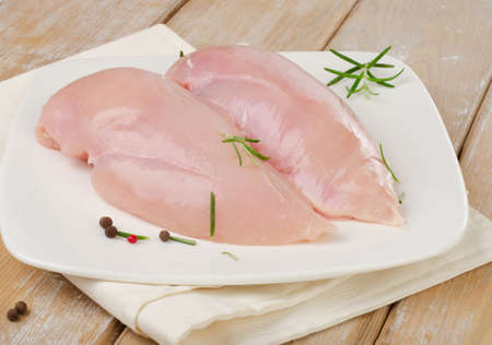 Raw chicken breast fillets on a white plateの写真素材
