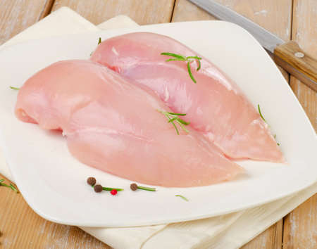 Raw chicken breast fillets on a white plateの写真素材