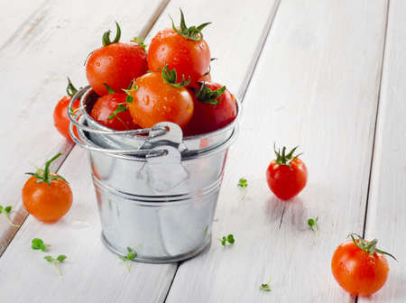 Fresh  cherry tomatoes with herbs on a wooden table. Selective focusの写真素材