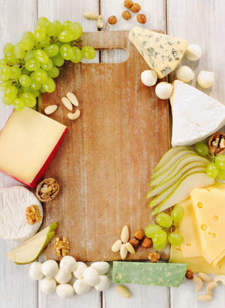 various types of cheese with fruits and nuts on a wooden tableの写真素材