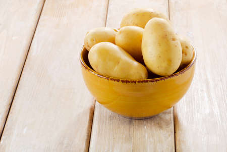 New potatoes in a bowl on wooden tableの写真素材