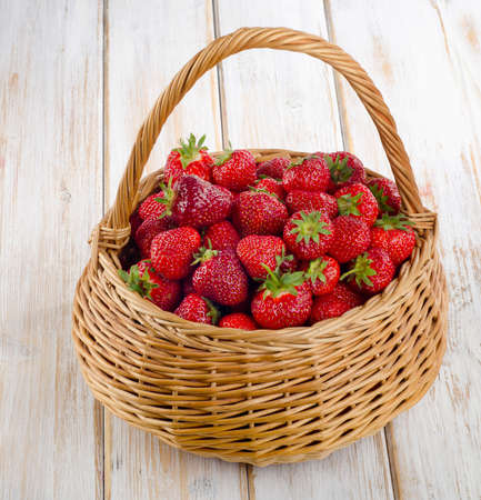Fresh strawberries in the basket on a wooden table.の写真素材