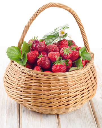 Fresh strawberries in the basket on a wooden table isolated on whiteの写真素材