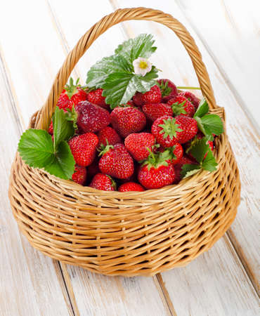 Fresh strawberries in the basket on a wooden table.の写真素材