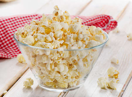 Popcorn in glass bowl on a wooden table. Selective focusの写真素材