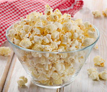 Popcorn in glass bowl on a wooden table. Selective focusの写真素材