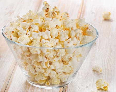Popcorn in glass bowl on a wooden table. Selective focusの写真素材