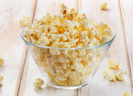 Popcorn in glass bowl on a wooden table. Selective focusの写真素材