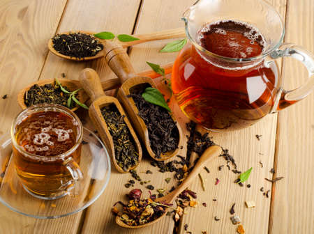 Cup of tea and assortment of dry tea in spoon on a  wooden background. Selective focusの写真素材