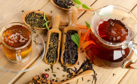 Cup of tea and assortment of dry tea in spoon on a  wooden background. Selective focusの写真素材