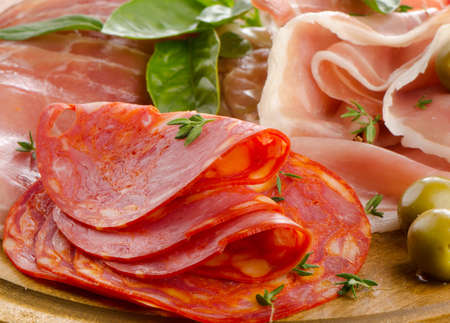 Slices of cured ham and  chorizo on a wooden table . Selective focusの写真素材