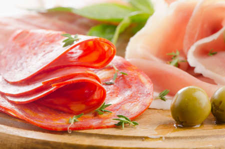 Slices of cured ham and  chorizo on a wooden table . Selective focusの写真素材