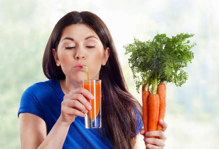 Young   woman drinking fresh carrot juiceの写真素材