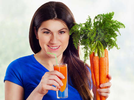 Young  smiling woman drinking fresh carrot juiceの写真素材
