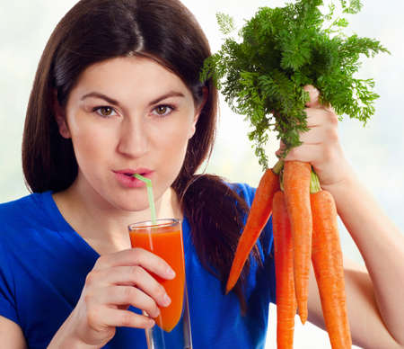 Young  smiling girl drinking fresh carrot juiceの写真素材