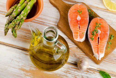 Healthy food  ingredients - salmon, vegetables and olive oil on a wooden tableの写真素材