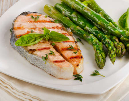 Grilled salmon with asparagus  and fresh herbs on white plate. Selective focusの写真素材