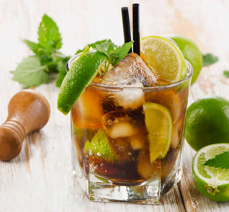 Glass of cocktail with rum, lime, mint  and ice on a wooden table. Selective focusの写真素材