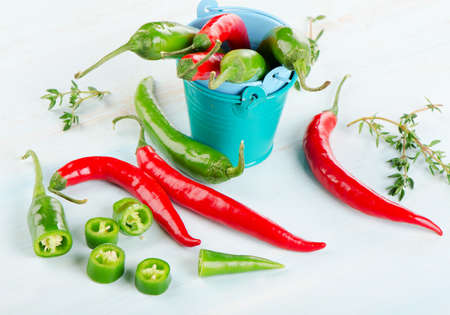 Red and green Chili Peppers with herbs on  wooden table.  Selective focusの写真素材