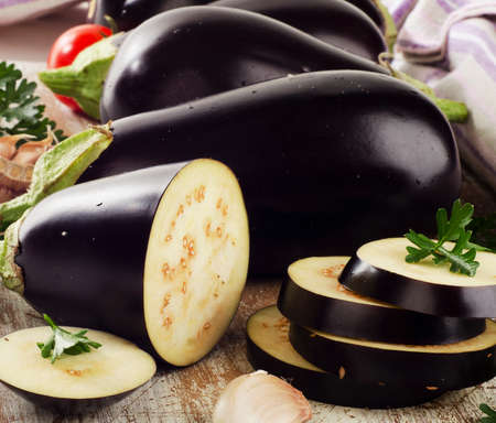 Eggplants with fresh  herbs on wooden board. Selective focusの写真素材