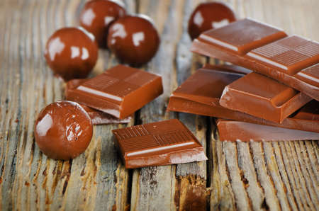 Broken chocolate bar and candies  on  wooden table. Selective focusの写真素材