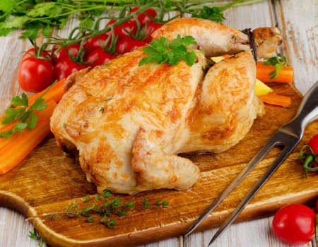 whole roasted chicken with vegetables on a cutting board.の写真素材