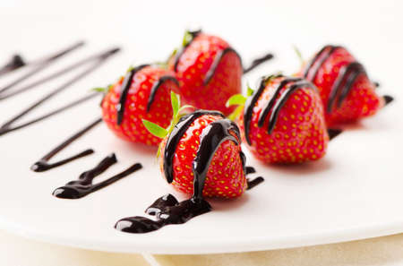Fresh strawberries dipped in chocolate sauce on a white plate. Selective focusの写真素材