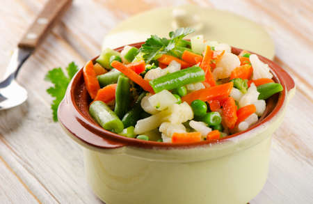 Mixed vegetables in a bowl on a wooden tableの写真素材