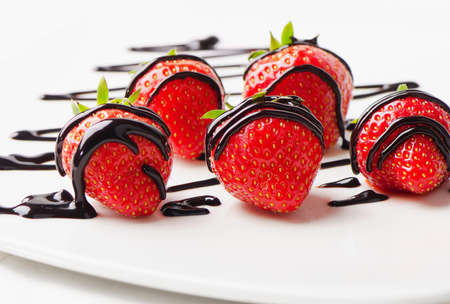 Strawberries dipped in chocolate sauce on white plate. Selective focusの写真素材