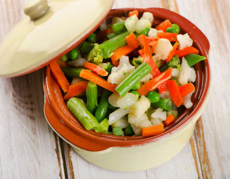 Vegetables in clay  bowl on a wooden tableの写真素材